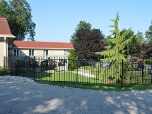 A building with a low black metal fence around a garden and walkway 